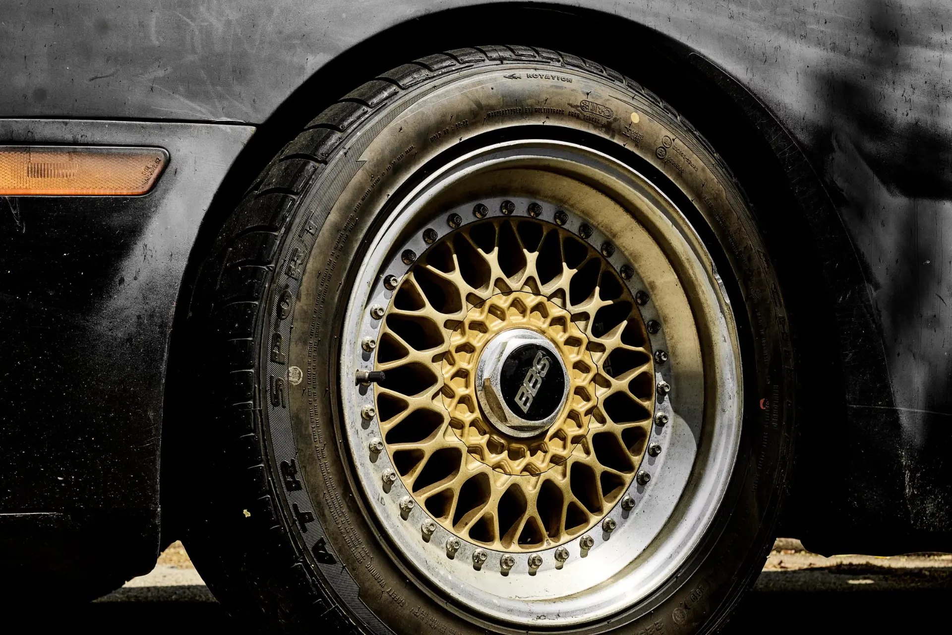 Gold multi-spoke alloy wheel with silver lip on a dark vehicle